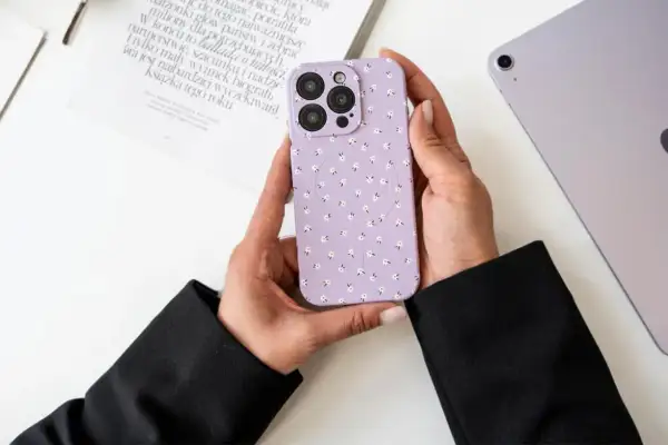 Ręce trzymają fioletowe etui na telefon w kwiatki. Dowiedz się, jak wyczyścić matowe etui, aby wyglądało jak nowe.