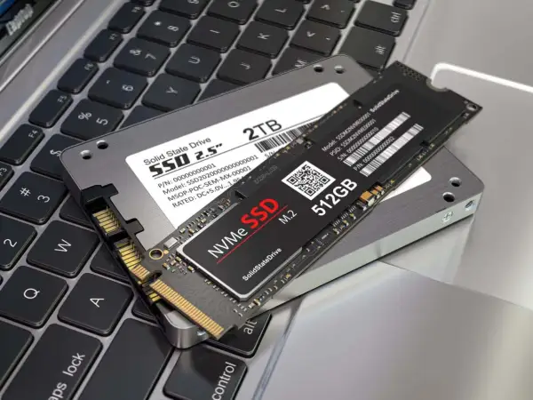 Dwa dyski SSD: 2,5-calowy NGFF i mniejszy NVMe M.2, leżące na klawiaturze laptopa.